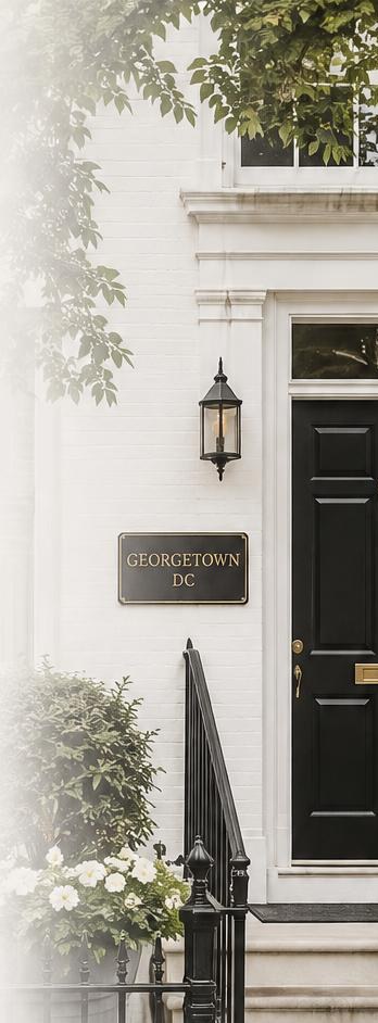 White brick Georgetown townhouse with a black front door, lantern, and flower boxes.